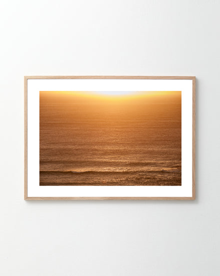 The Ikaros Poster showcases a serene ocean scene at sunset, where the sun hovers near the horizon, casting a warm golden glow over the water and creating a peaceful atmosphere.