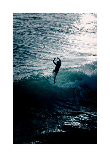 Man surfing a right-hander wave one a blue ocean reflecting white in the sun.