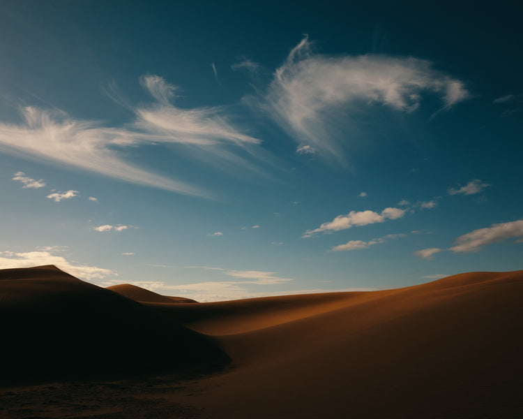 Dessert landscape with brown sand dunes under a clear blue sky.