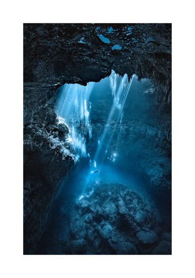 Divers exploring a deep blue water cave.