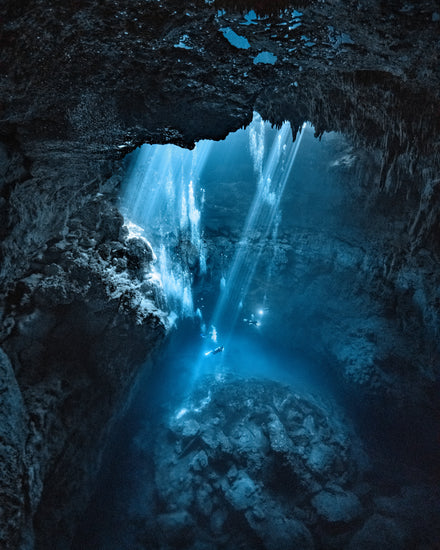 Divers exploring a deep blue water cave.