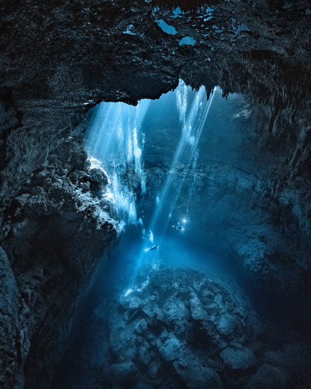 Divers exploring a deep blue water cave.