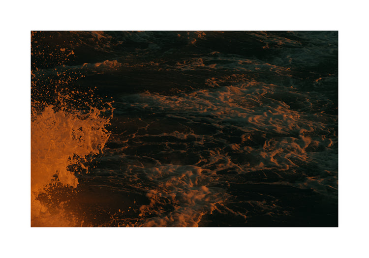 Rushing sea with foam colored crimson by the setting sun.