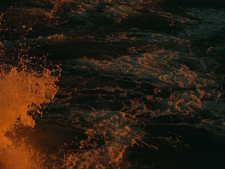 Rushing sea with foam colored crimson by the setting sun.