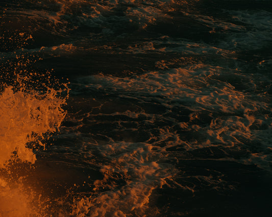 Rushing sea with foam colored crimson by the setting sun.