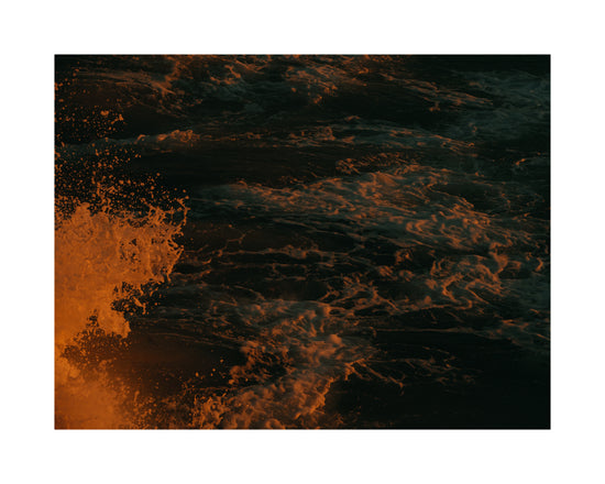 Rushing sea with foam colored crimson by the setting sun.