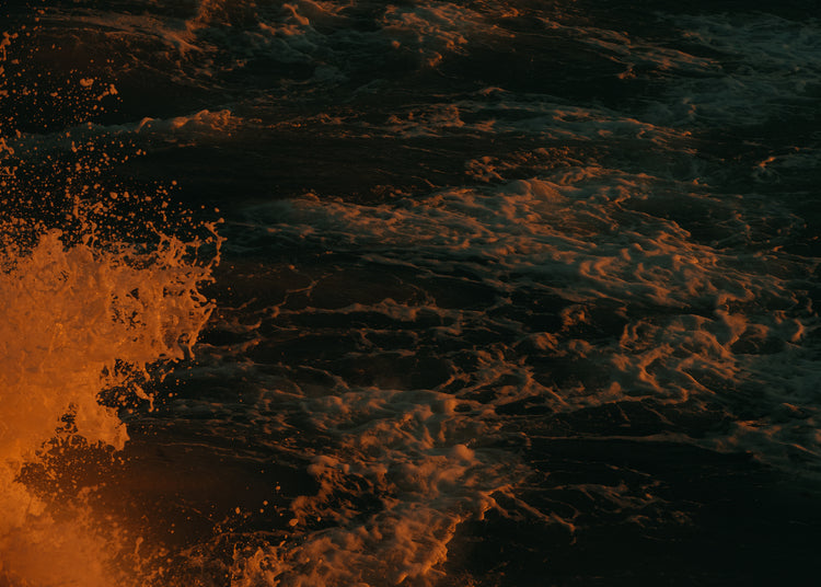 Rushing sea with foam colored crimson by the setting sun.