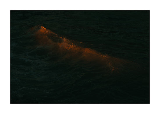 Waves colored orange from the setting sun in the ocean.