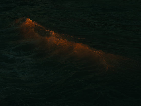 Waves colored orange from the setting sun in the ocean.