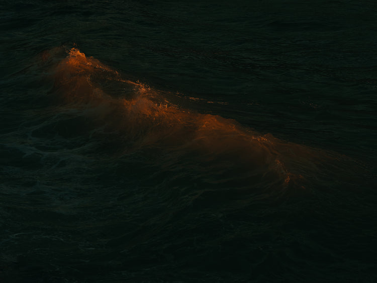 Waves colored orange from the setting sun in the ocean.