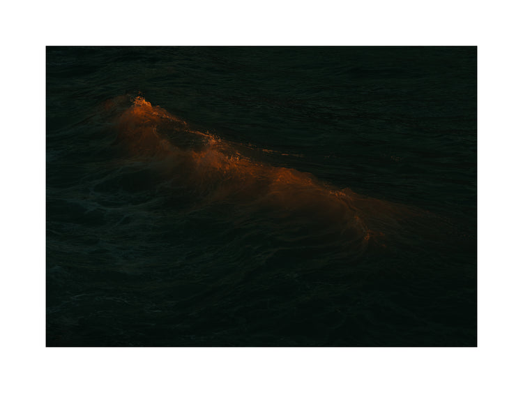 Waves colored orange from the setting sun in the ocean.