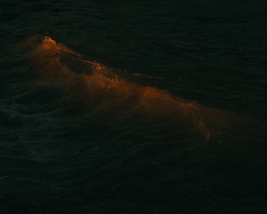 Waves colored orange from the setting sun in the ocean.