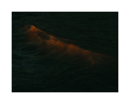 Waves colored orange from the setting sun in the ocean.