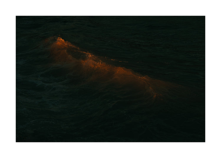 Waves colored orange from the setting sun in the ocean.