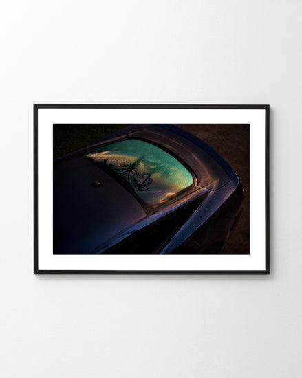 The Gas Up Poster captures a sleek car with dew on the windshield under a vibrant sky, embodying pedal to the metal. Displayed on a plain white wall and viewed from an elevated angle, it highlights dynamic presence.