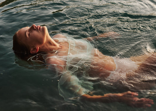 Woman dressed in white floating at the surface of the ocean.