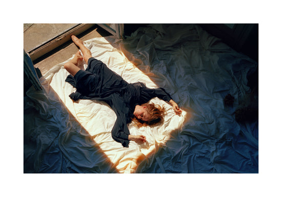 Woman in a blue dress laying in the sun coming in through an open door.