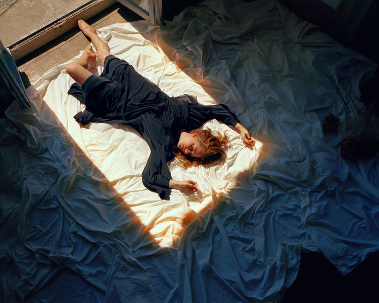 Woman in a blue dress laying in the sun coming in through an open door.